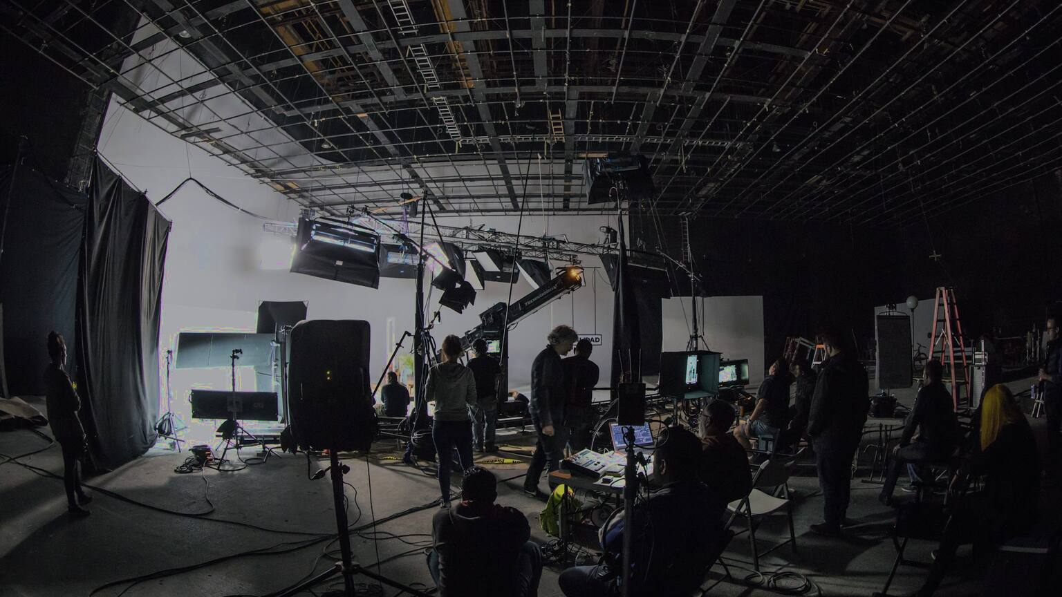 A film crew at work on a lit set at night.