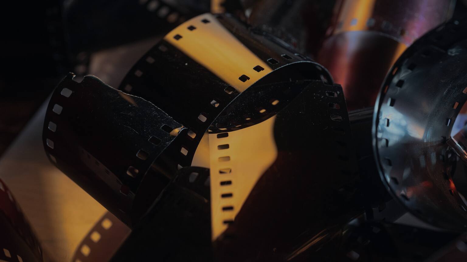Coiled strips of motion picture film in warm light.