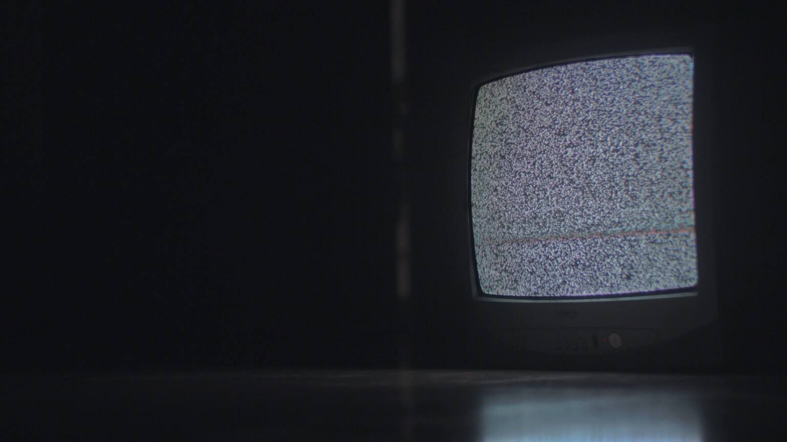 A living-room television glowing in a dark room.